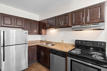 A kitchen with a stove, refrigerator, and cabinets.